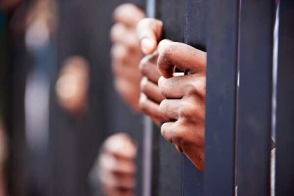 handen van gevangenen achter tralies van een cel